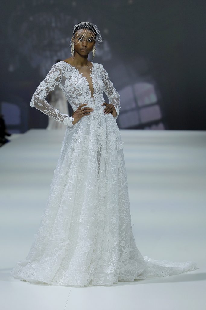 In questa foto la modella indossa un abito da sposa con motivi floreali a maniche lunghe.