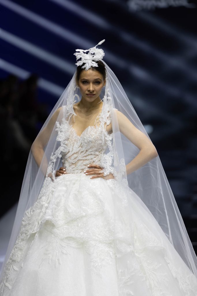 In questa foto la modella indossa un abito da sposa Amelia Casablanca 2023 con decori floreali.