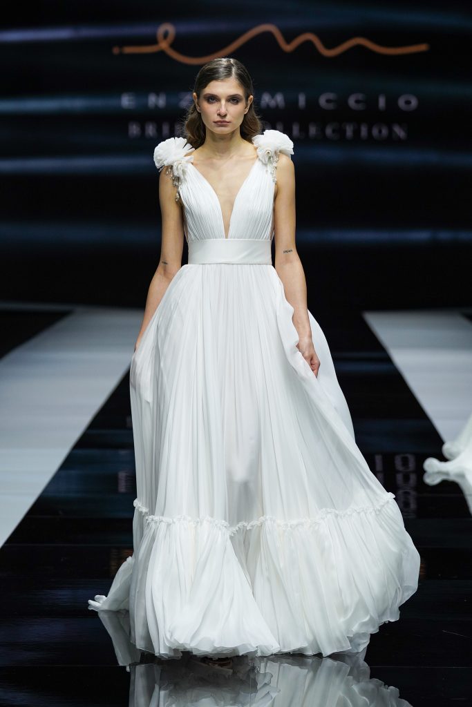 In questa foto la modella indossa un abito da sposa Enzo Miccio 2023 con scollo a V e balza.