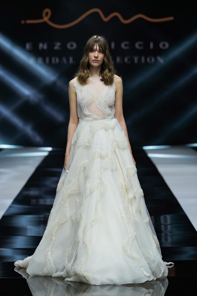 In questa foto la modella indossa un abito da sposa Enzo Miccio 2023 con decori ad onde.