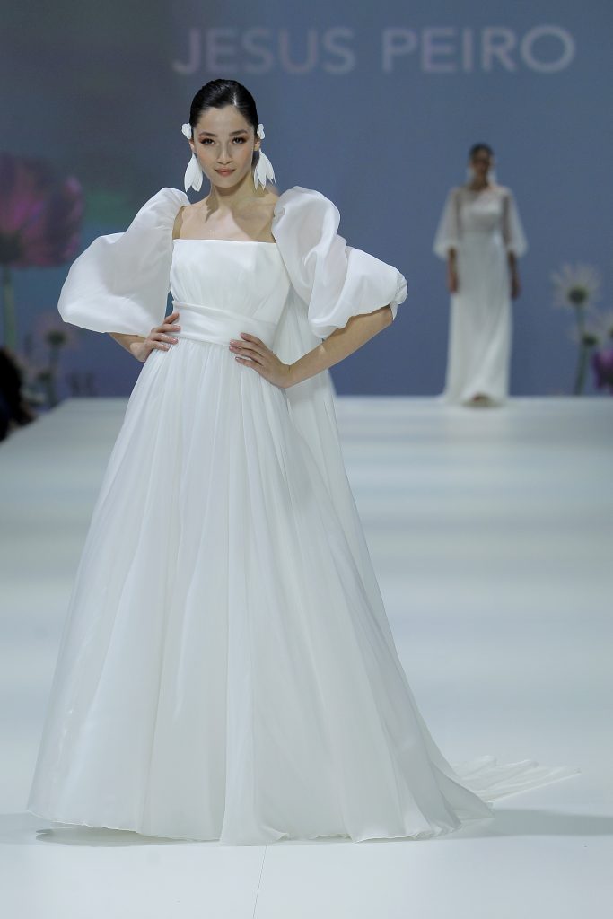 In questa foto al modella indossa un abito da sposa Jesus Peiro 2023 con gonna ampia e maniche baloon.