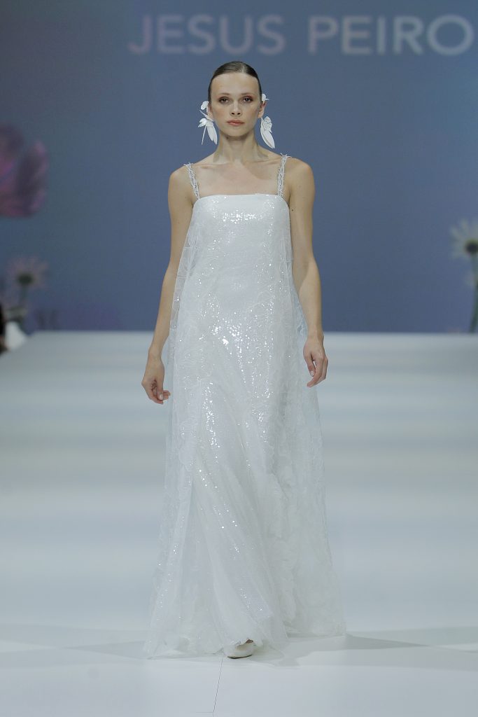 In questa foto al modella indossa un abito da sposa Jesus Peiro 2023 con tessuto di paillettes.