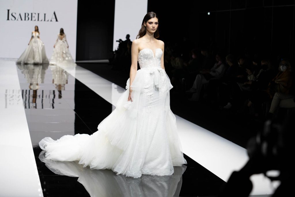 In questa foto la modella indossa un abito da sposa Maison Signore 2023 con una ampia sopragonna in tulle.