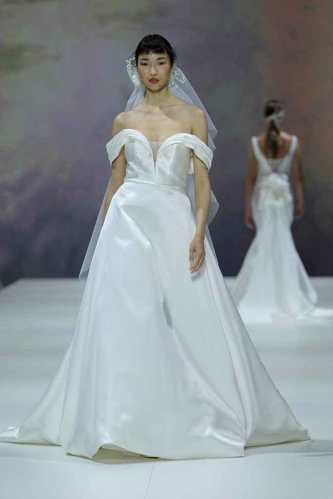 In questa immagine la modella indossa un abito da sposa della collezione di abiti da sposa Marchesa for Pronovias 2023 con maniche scivolate.