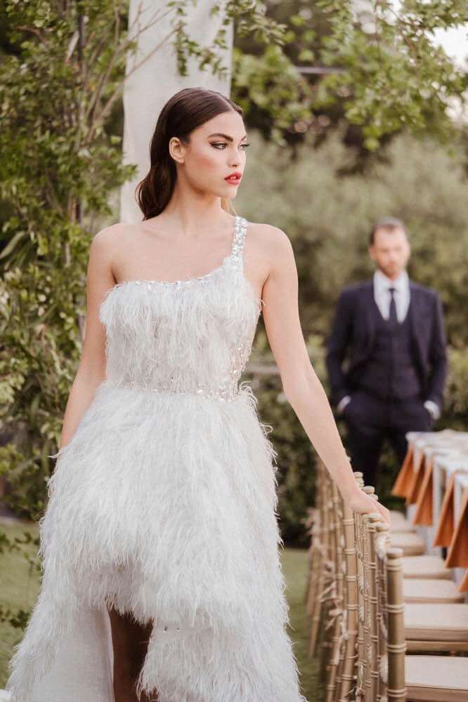 In questa foto una modella indossa un abito da sposa monospalla 2022 della collezione Luisa Sposa