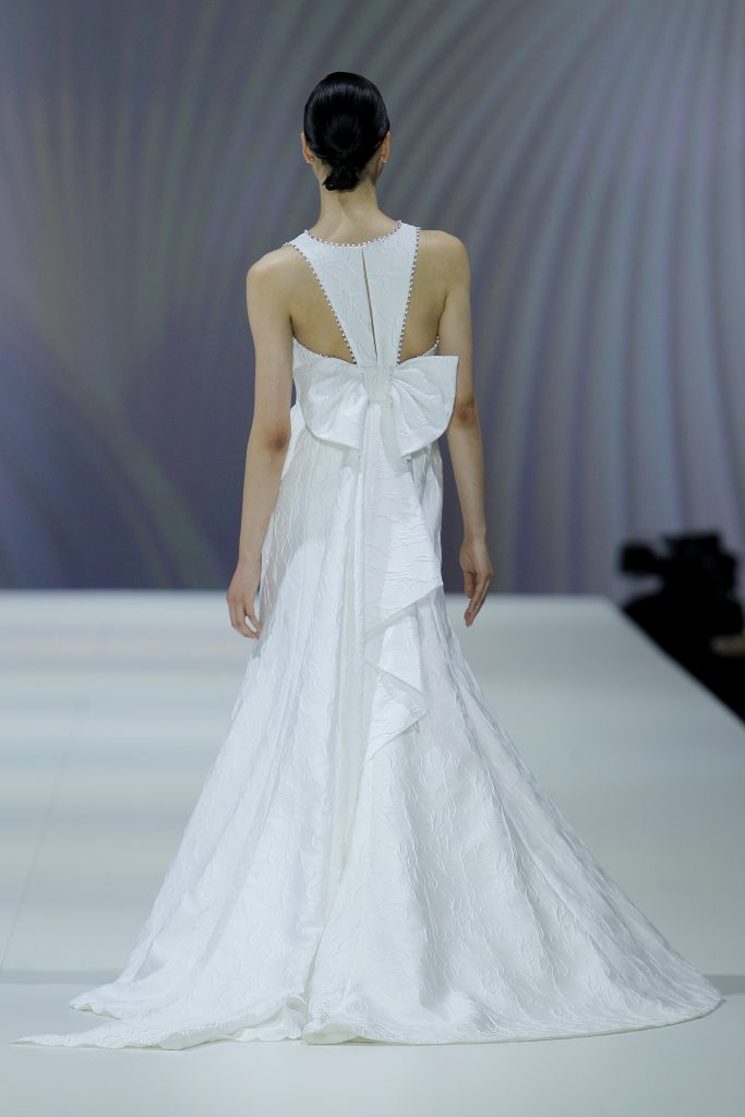 In questa foto la modella indossa un abito da sposa Nicole Milano 2023  con maxi fiocco.