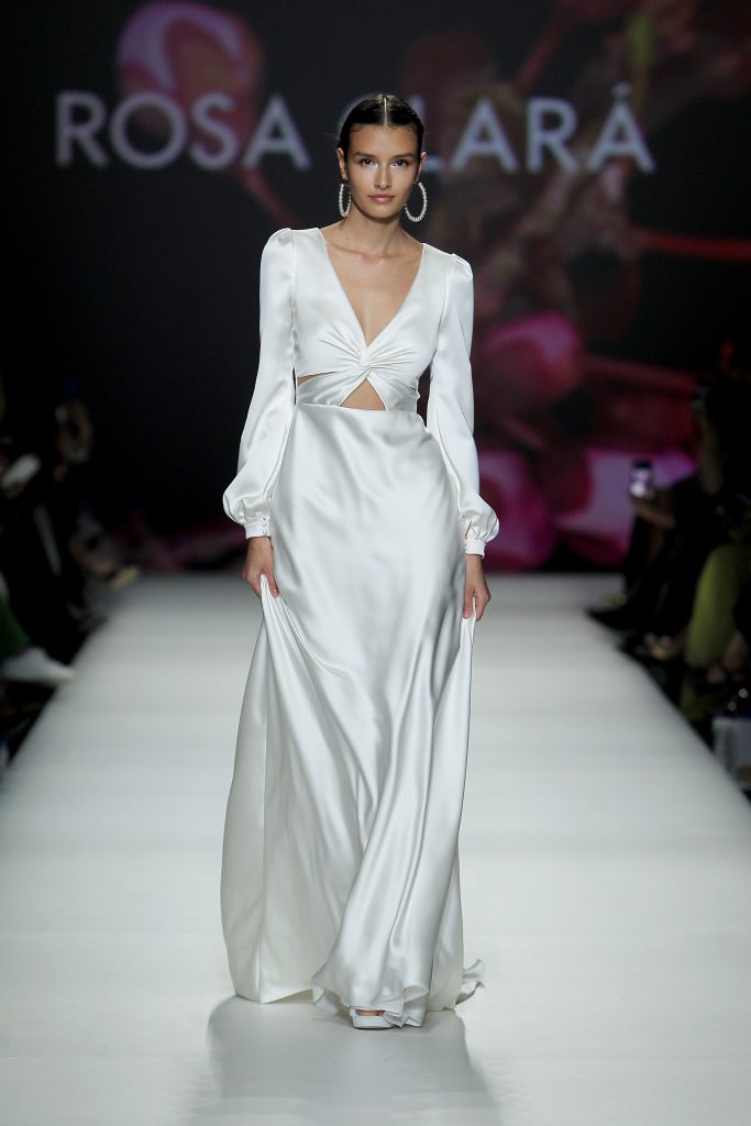 In questa foto la modella indossa un abito da sposa Rosa Clarà 2023 di seta con maniche lunghe.