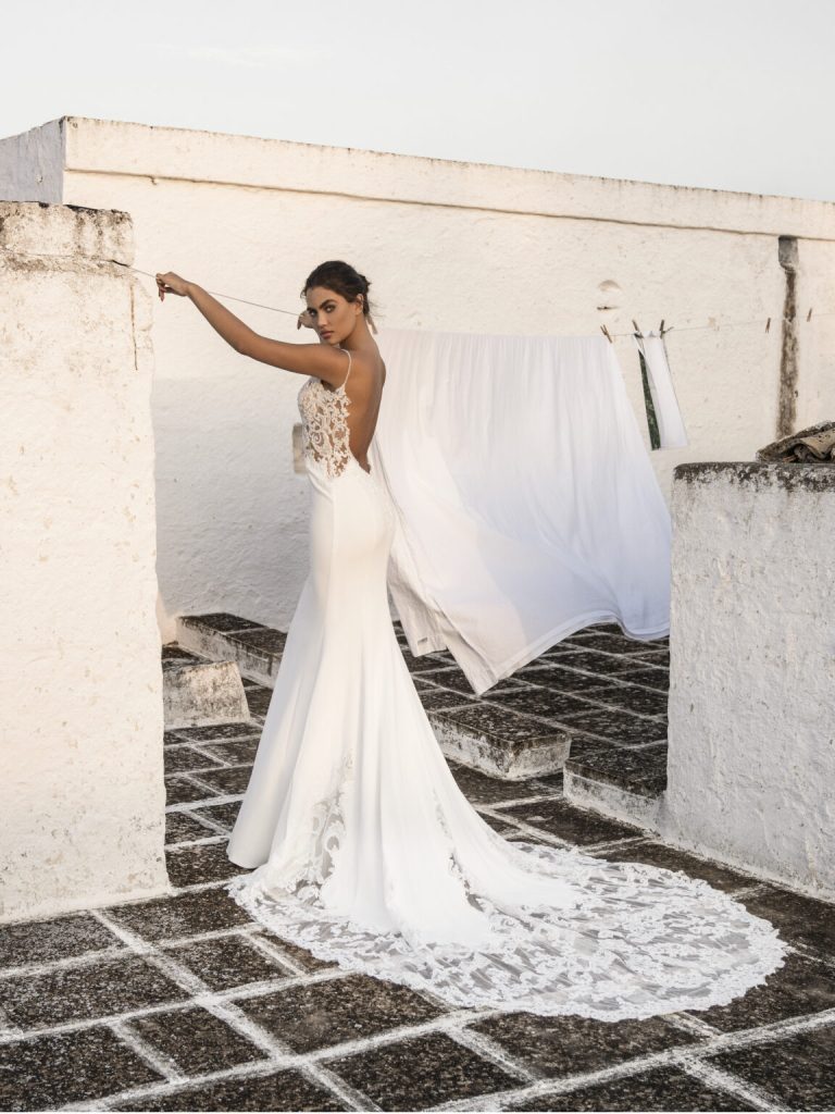 In questa foto una modella indossa un abito da sposa schiena scollata 2022 della collezione Alessandro Aneglozzi couture con scollo di pizzo.