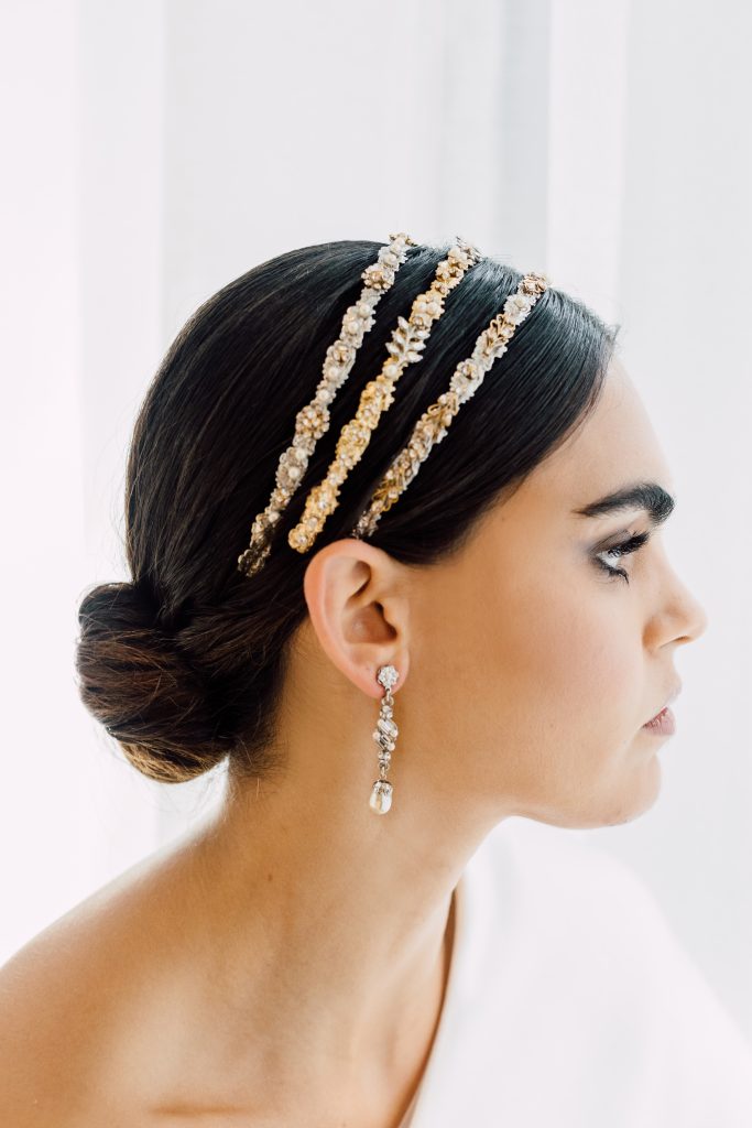 In questa foto una modella di profilo indossa un cerchietto da sposa a tre fasce con perline colore oro 