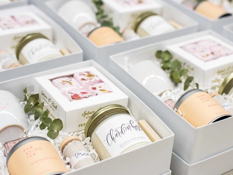 In questa foto bomboniere per matrimonio in scatole bianche con piccoli barattoli in vetro, confetti, candele e tazze