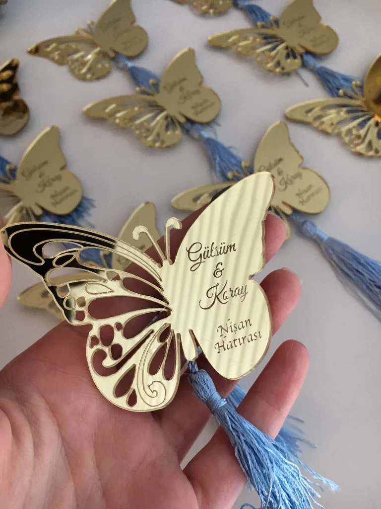 In questa foto calamite colore oro a forma di farfalla con nappa turchese come bomboniere di nozze