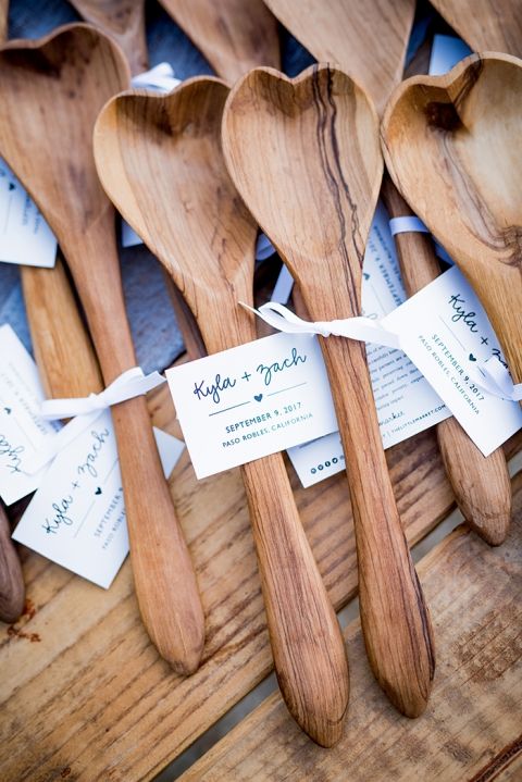 In questa foto cucchiai di legno a forma di cuore come bomboniere per matrimonio con biglietto con i nomi degli sposi e la data delle nozze