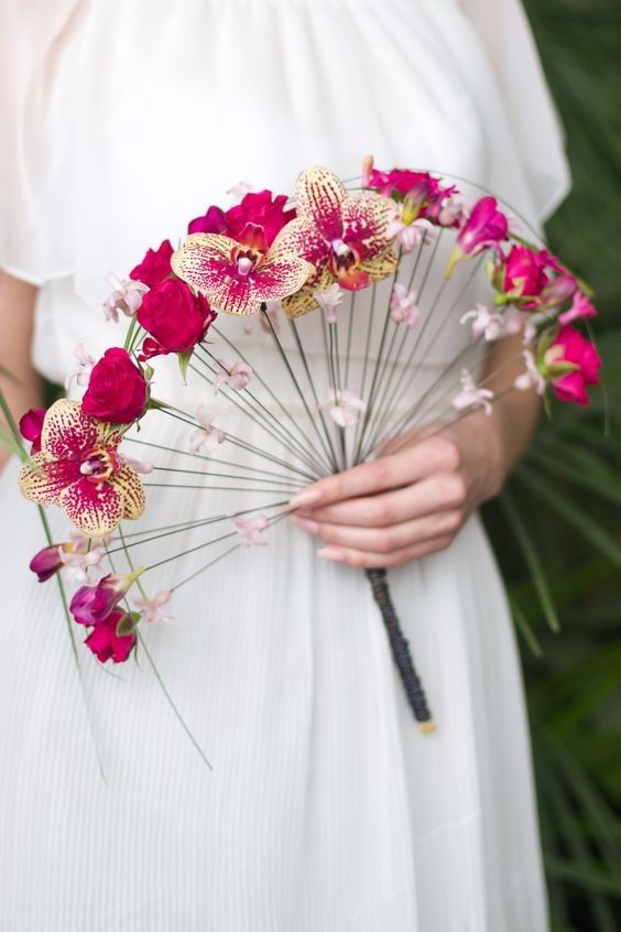 In questa foto un bouquet a ventaglio con rose e orchidee fucsia e piccoli fiori rosa