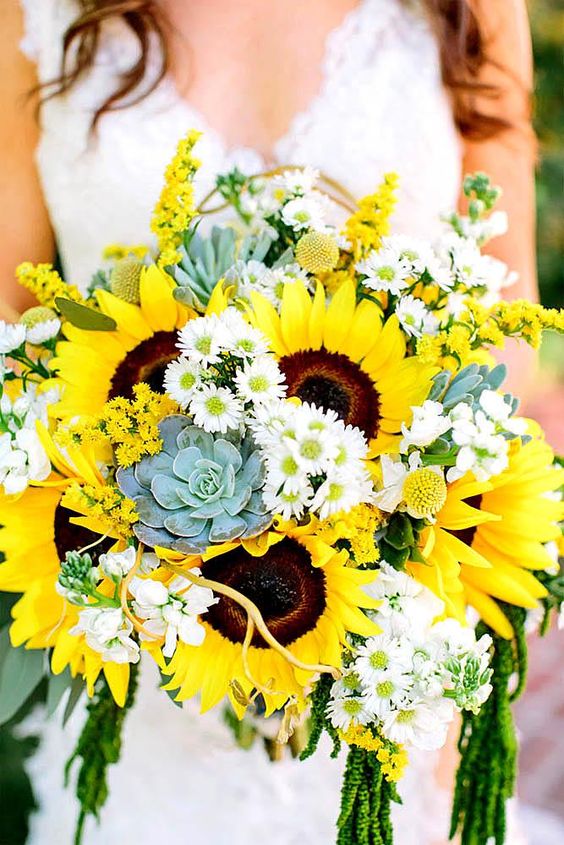 In questa foto le mani di una sposa che tengono un bouquet di girasoli, succulente e margherite