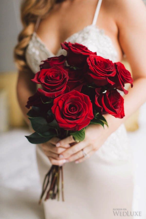 in questa foto una sposa che tiene tra le mani un mazzo di rose rosse