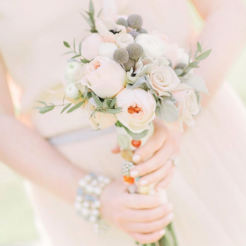 In questa foto un bouquet posy di peonie rosa, rose colore rosa, craspedia beige, fiori di cotone e foglioline