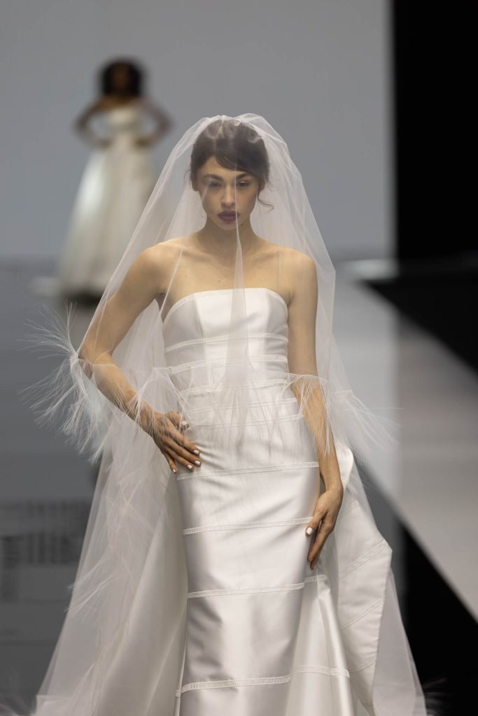 In questa foto la modella indossa un abito della collezione sposa Giuseppe Papini 2023 a sirena con velo con piume.
