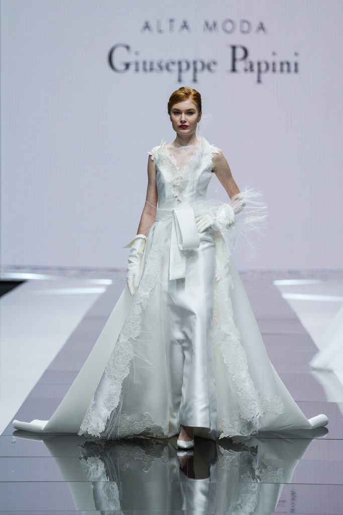 In questa foto la modella indossa un abito della collezione sposa Giuseppe Papini 2023 con bordure di pizzo e piume.