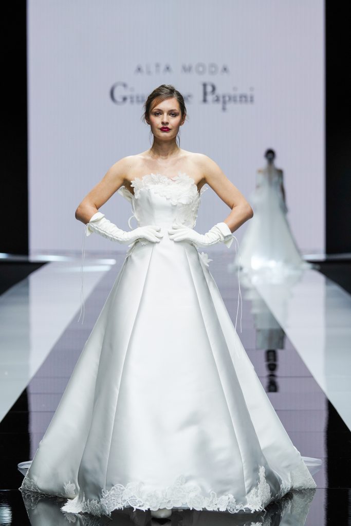 In questa foto la modella indossa un abito della collezione sposa Giuseppe Papini 2023 con gonna ampia e guanti.