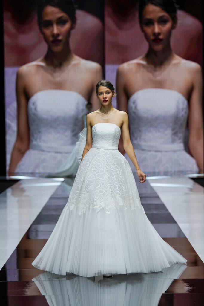 In questa foto la modella indossa un abito da sposa Giuseppe Papini 2023 con gonna ricamata e tessuto plissettato.