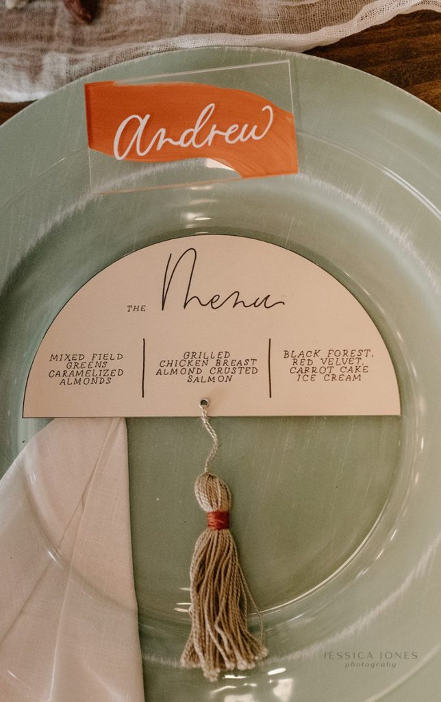 In questa foto un menù per matrimonio originale a forma di mezzaluna con nappa di colore beige legata al centro