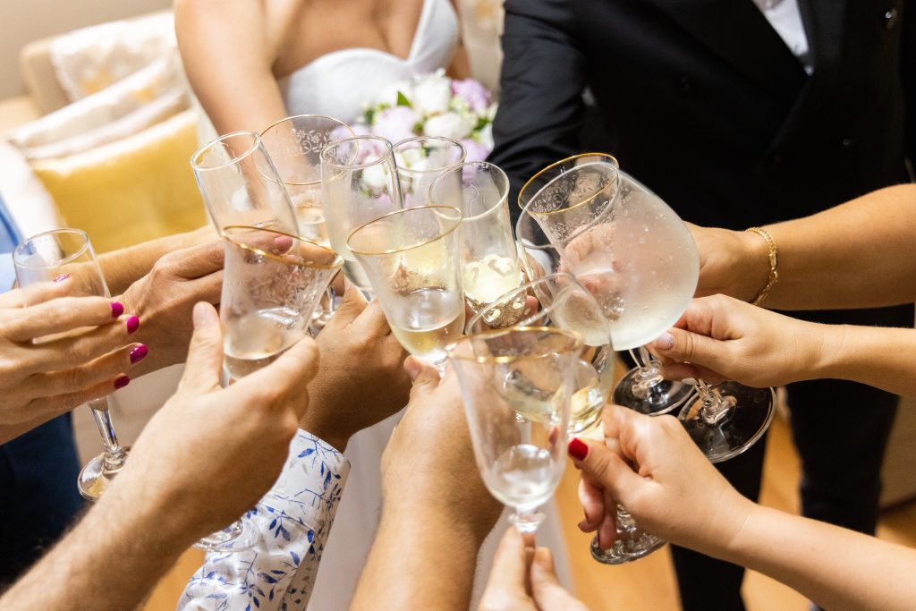 In questa foto le mani di sposi e invitati che brindano con calici di vino