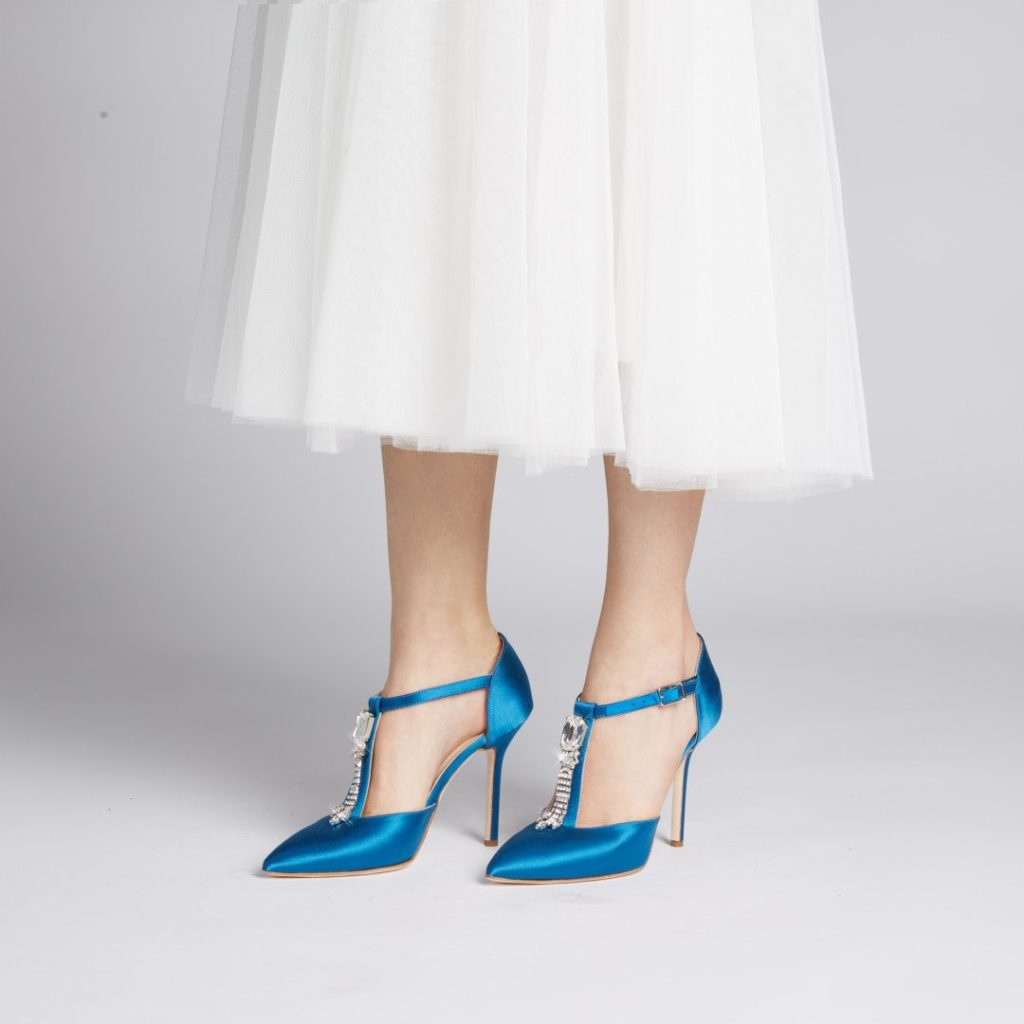In questa foto le gambe di una modella che indossa scarpe da sposa colore blu elettrico con fascia di strass sul collo del piede