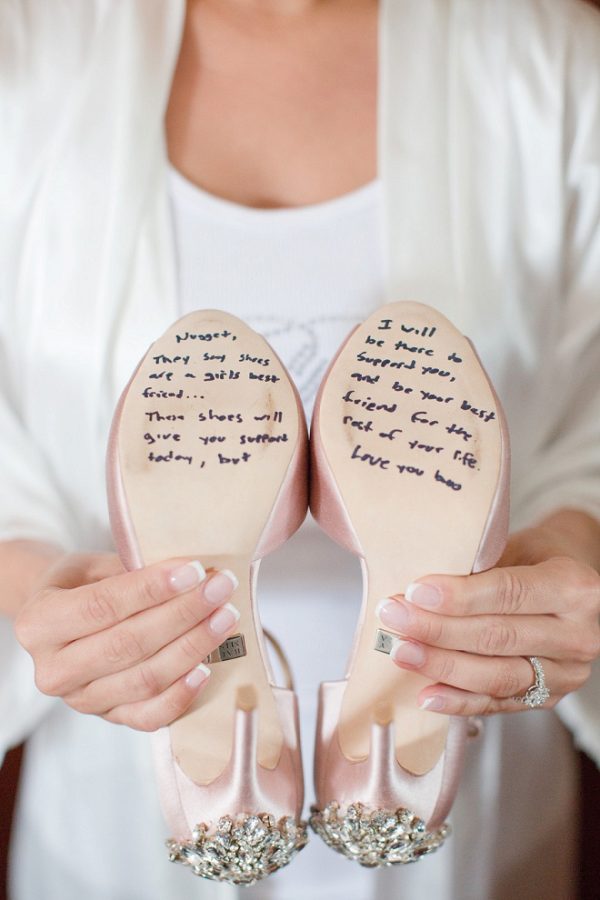 In questa foto una sposa mostra le suole delle sue scarpe rosa gioiello con scritto un. testo in inglese