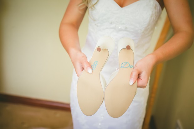In questa foto una sposa mostra le suole delle sue scarpe con la scritta "I do" realizzata con strass colore argento