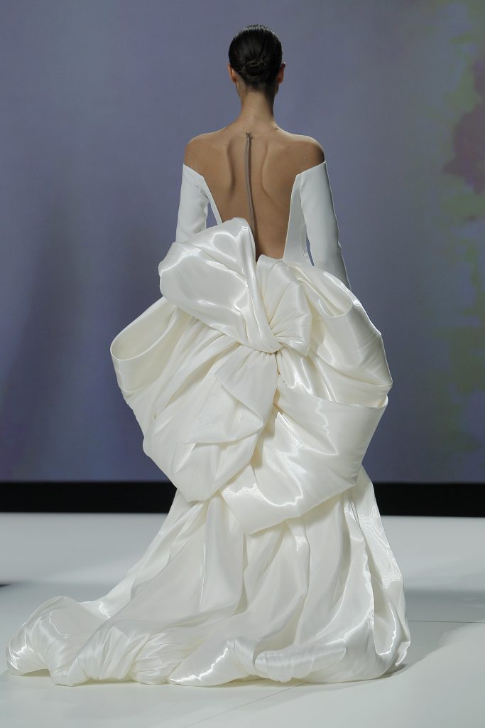 In questa foto la modella indossa un abito da sposa Isabel Sanchís 2023 con maxi volume sul retro e profondo scollo