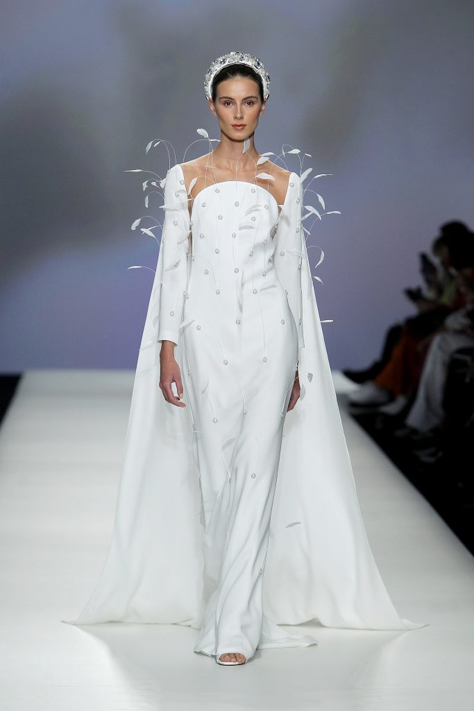 In questa foto la modella indossa un abito da sposa con mantello e piume.