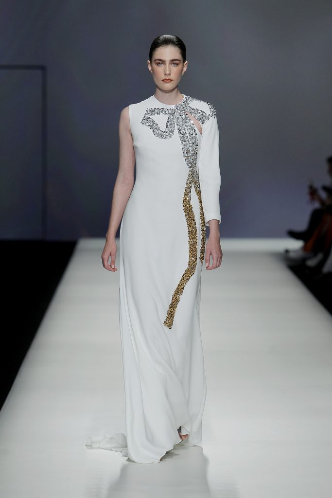 In questa foto la modella indossa un abito da sposa Isabel Sanchís 2023 con maxi fiocco ricamato in argento e oro.