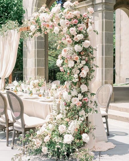 In questa foto, una tavola decorata con una cascata di rose bianche e rosa. Una scelta ideale per fiori matrimonio stile classico