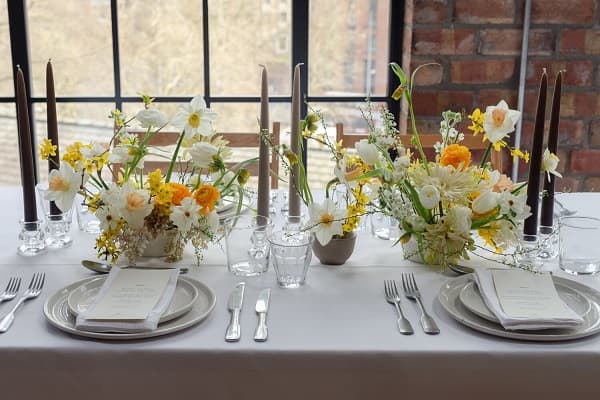 In questa foto, piccole composizioni floreali dai colori neutri decorano la mise en place di un matrimonio industrial style