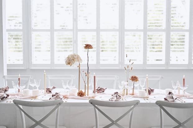 In questa foto, la mise en place è allestita con singoli fiori sistemati all'interno di piccoli vasi per un matrimonio minimal chic