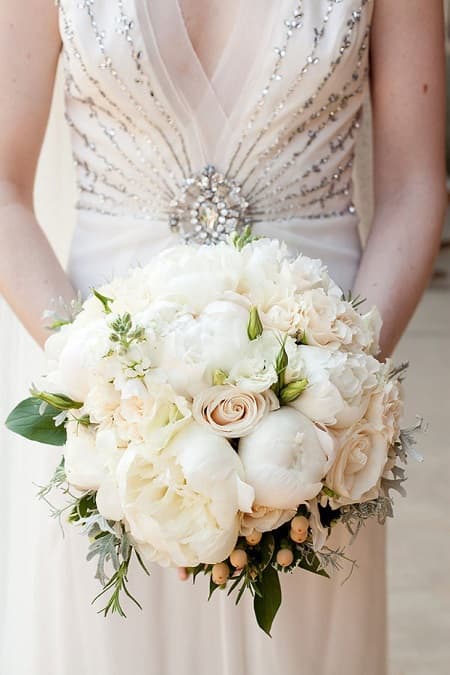 In questa foto, un bouquet rotondo ideato con peonie bianche e rose avorio rappresenta lo stile fiori matrimonio vintage 
