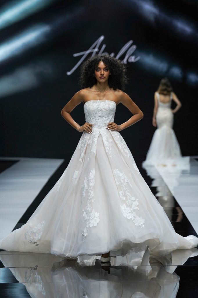 In questa foto la modella indossa un abito da sposa Allure Bridals 2023 con corsetto e gonna ampia di tulle.
