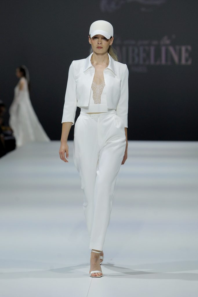 In questa foto la modella indossa un completo bianco da sposa con giacca corta e pantaloni.