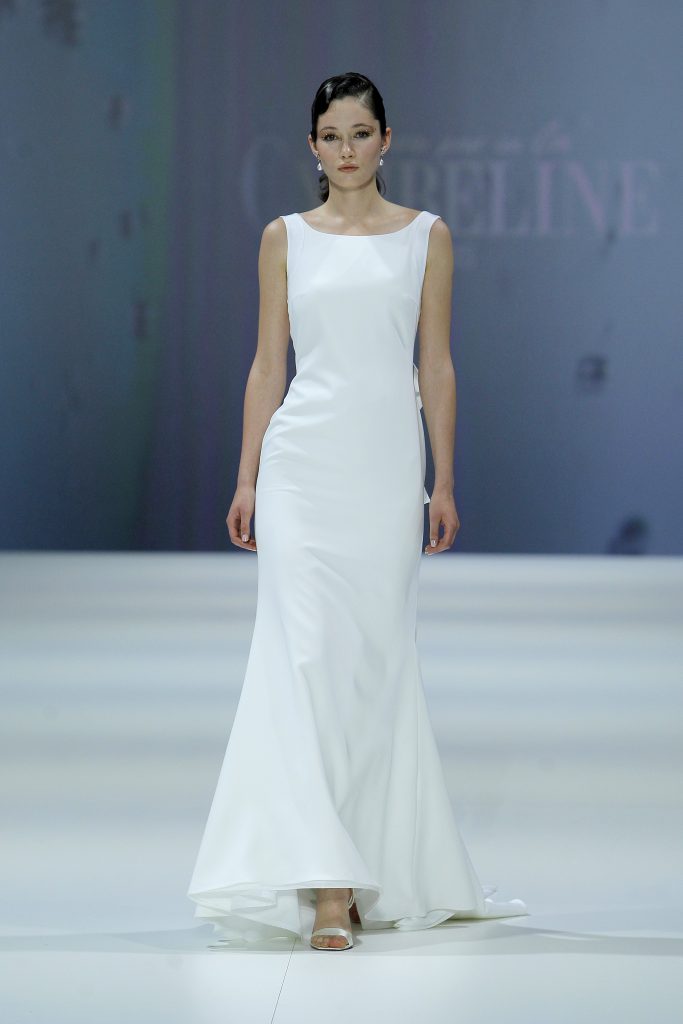 In questa foto la modella indossa un abito da sposa Cymbeline 2023 semplice con scollo leggermente a barca.