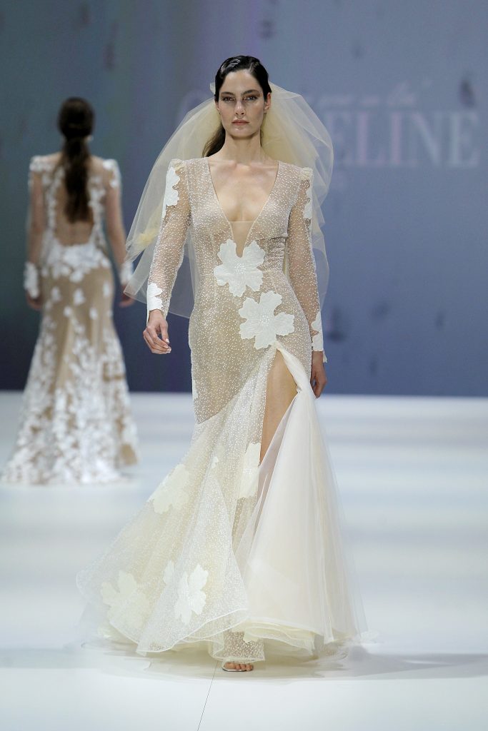In questa foto la modella indossa un abito da sposa nude Cymbeline 2023 con fiori bianchi.