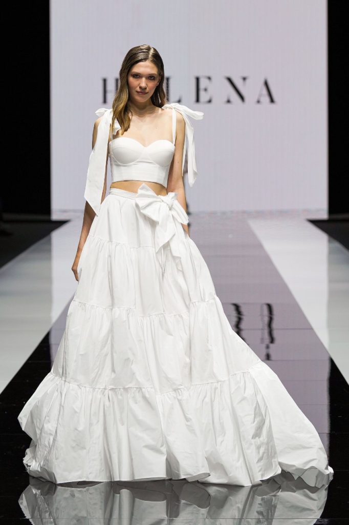 In questa foto la modella indossa un abito da sposa Helena 2023 con corsetto e gonna a balze.