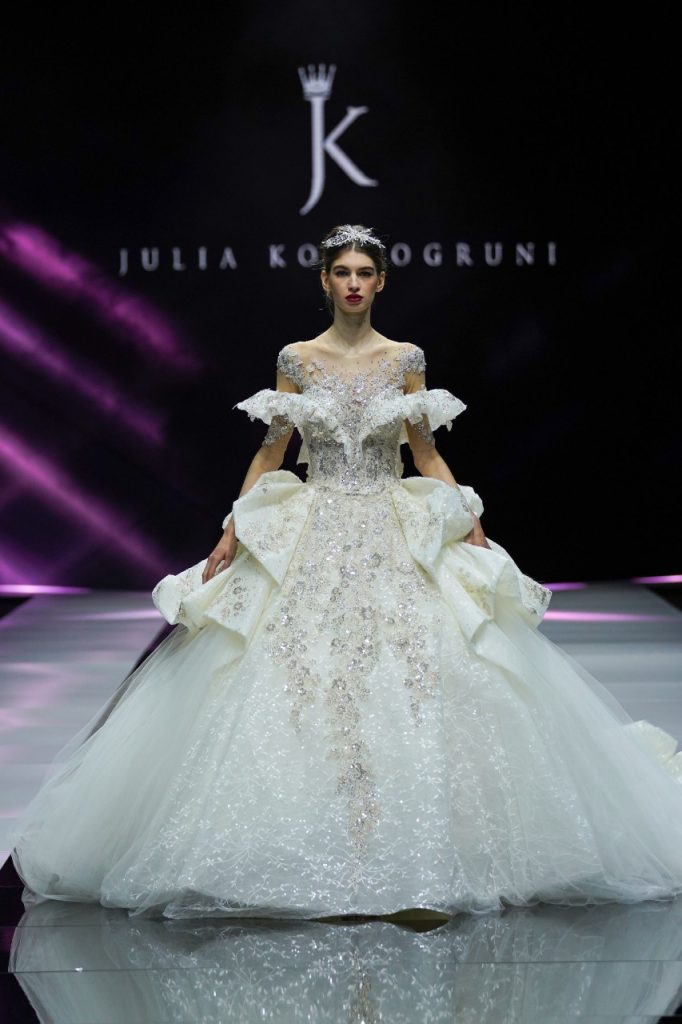 In questa foto la modella indossa un abito da sposa Julia Kontogruni 2023 ampio con ruches e cristalli.
