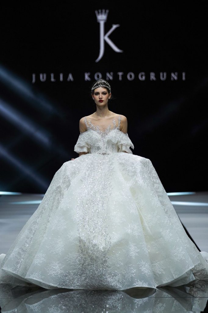 In questa foto la modella indossa un abito da sposa Julia Kontogruni 2023 ampio con ruches sulle maniche.