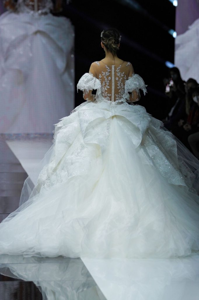 In questa foto la modella indossa un abito da sposa ampio con ruches e maxi fiocco sul retro.