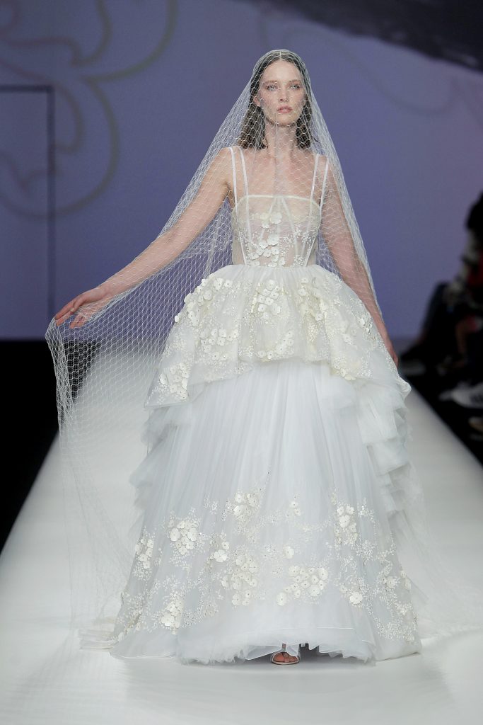 In questa foto la modella indossa un abito da sposa a balze di tulle con decori floreali.
