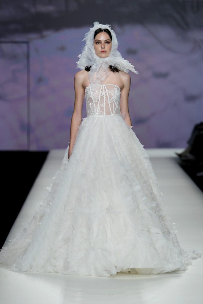 In questa foto la modella indossa un abito da sposa con gonna ampia e fiori.