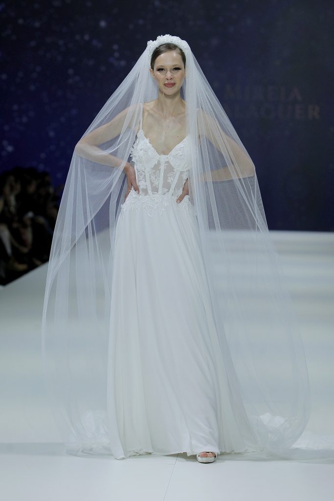 In questa foto la modella indossa un abito da sposa con velo di Mireia Balaguer 2023.