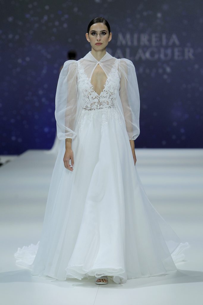 In questa foto la modella indossa un abito da sposa con scollo a V e maniche trasparenti di Mireia Balaguer.