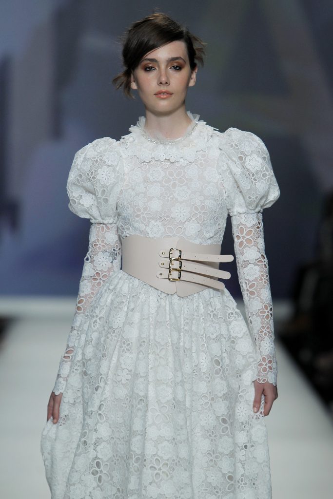 In questa foto la modella indossa un abito da sposa con maniche a sbuffo e pizzo fiorato di Poesie Sposa.
