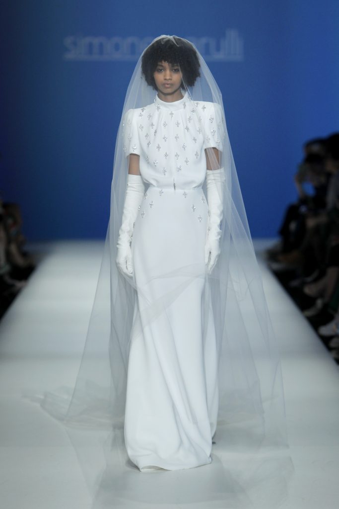 In questa foto la modella indossa un abito bianco con croci argento di Simone Marulli.